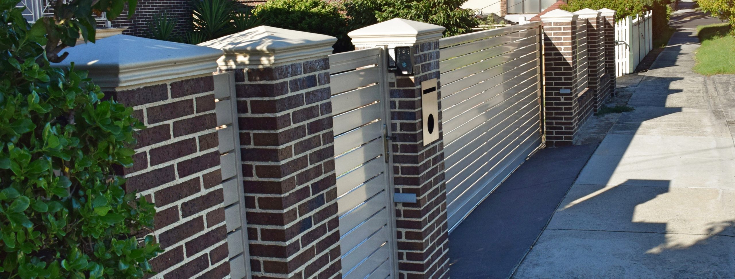 Brow brick pillar fence with aluminium infill panels designed and built by Custom Built Fences