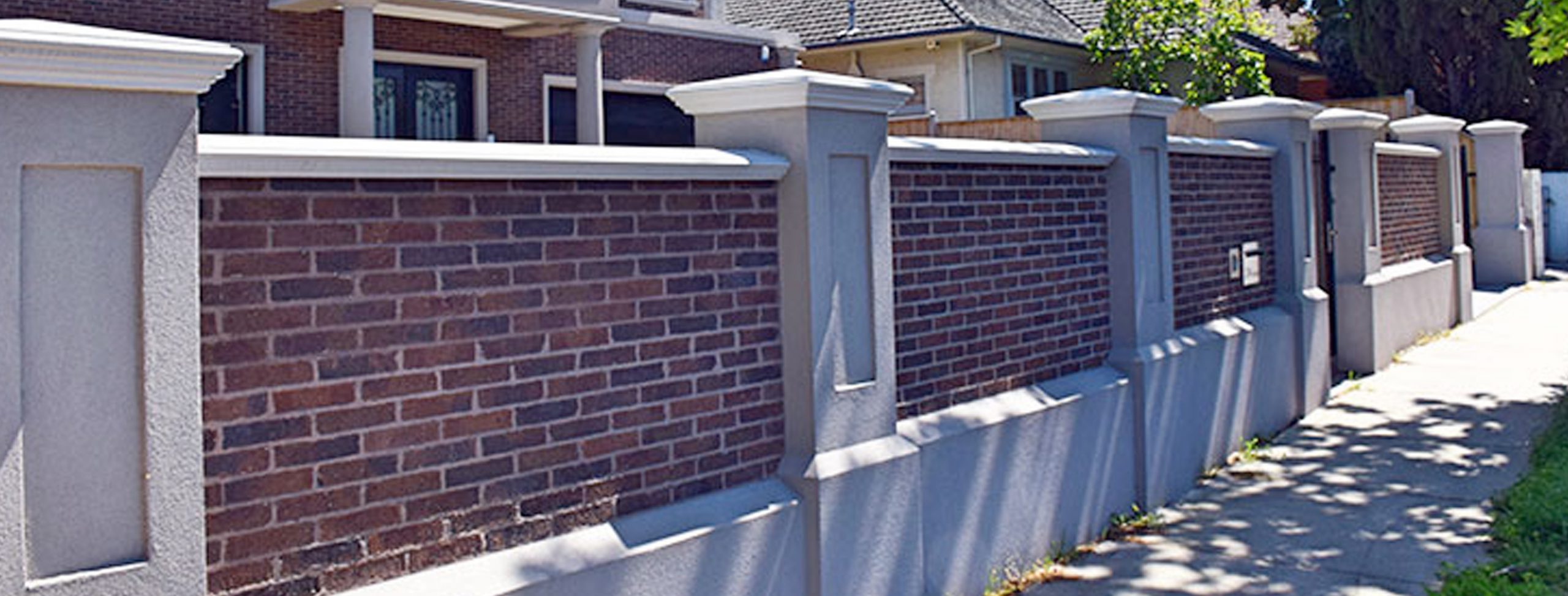 Rendered Pillars with brick infill wall designed and built by Custom Built Fences